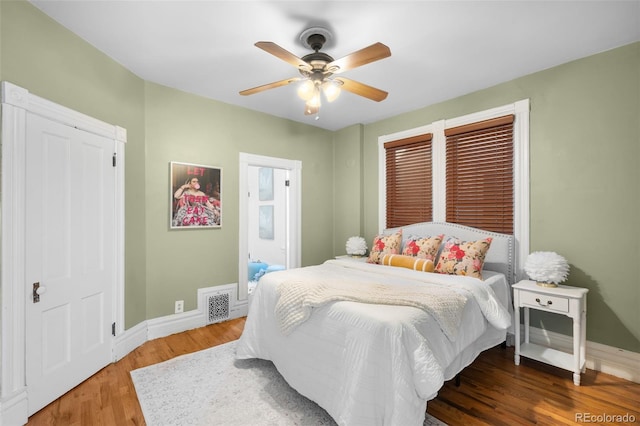 bedroom featuring visible vents, ceiling fan, baseboards, and wood finished floors