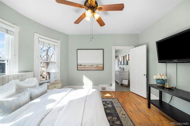 bedroom with visible vents, ceiling fan, baseboards, wood finished floors, and a sink