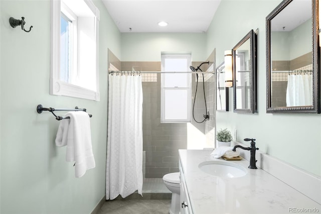 full bathroom with a tile shower, tile patterned flooring, toilet, and vanity