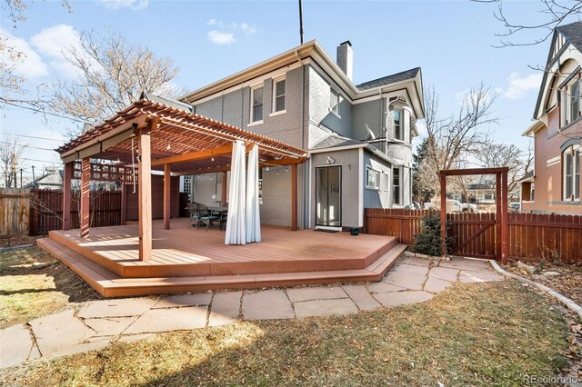 rear view of property with a deck, fence private yard, a chimney, and a pergola