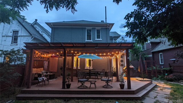 rear view of property featuring a wooden deck, brick siding, and a pergola