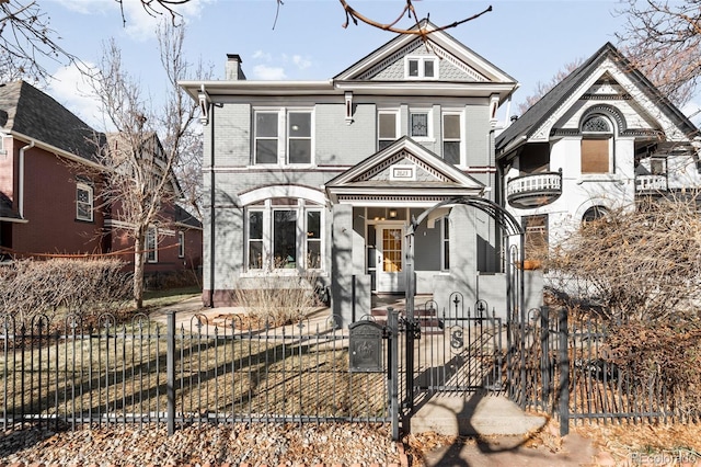 victorian home featuring a gate, brick siding, a fenced front yard, and a chimney