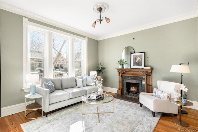 living area with ornamental molding, a fireplace, baseboards, and wood finished floors