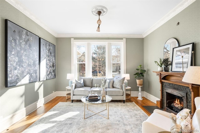 living area with a high end fireplace, ornamental molding, baseboards, and wood finished floors