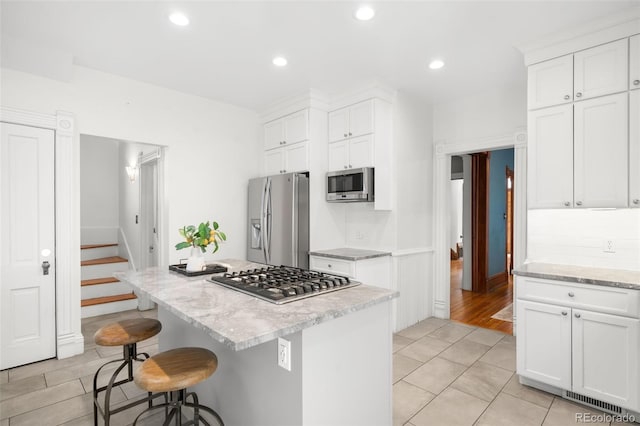 kitchen featuring stainless steel appliances, tasteful backsplash, a breakfast bar area, and white cabinetry