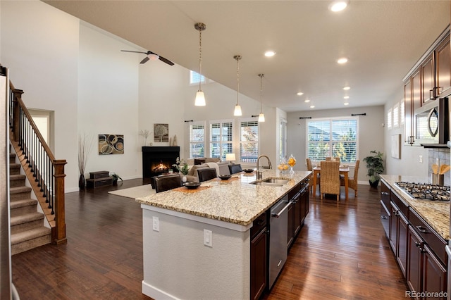 kitchen with stainless steel appliances, sink, a kitchen island with sink, dark hardwood / wood-style floors, and pendant lighting