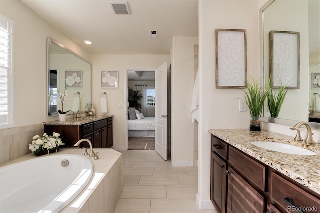 bathroom with vanity, tiled bath, and a healthy amount of sunlight