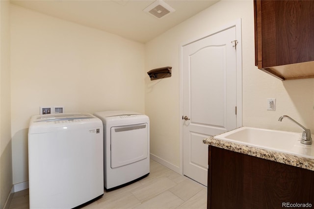 washroom with cabinets, washer and clothes dryer, and sink