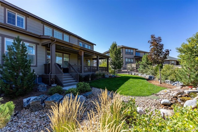 rear view of property featuring a porch and a lawn