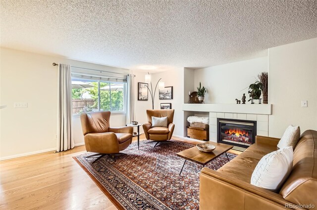 1641 Cedarwood Dr, Longmont, CO 80504 - living room with a textured ceiling, a tiled fireplace, light wood-style flooring, and baseboards