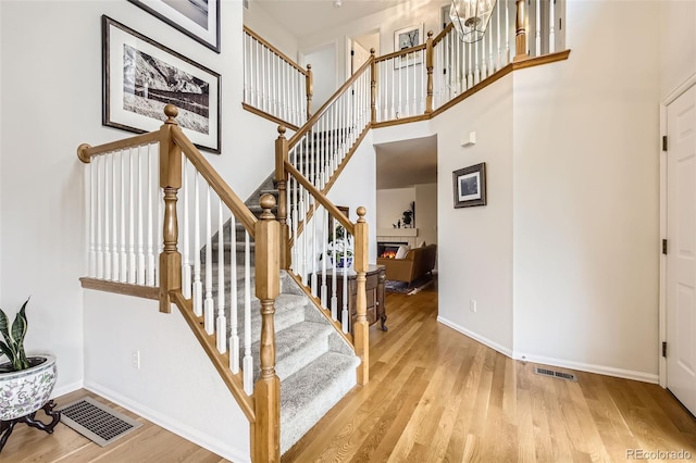 1641 Cedarwood Dr, Longmont, CO 80504 - stairs with wood finished floors, baseboards, a towering ceiling, and a glass covered fireplace