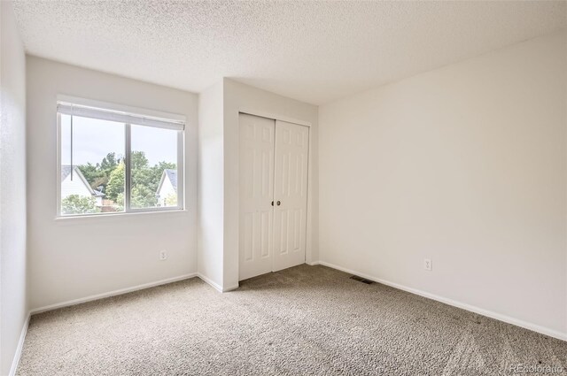 1641 Cedarwood Dr, Longmont, CO 80504 - unfurnished bedroom with carpet floors, a closet, baseboards, and a textured ceiling