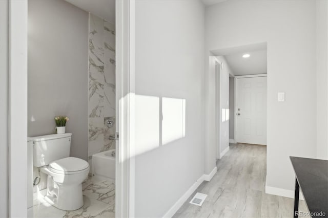 full bathroom featuring vanity, wood-type flooring, tiled shower / bath combo, and toilet