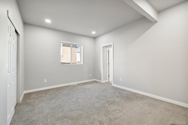 carpeted empty room with beam ceiling