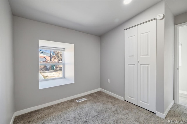 unfurnished bedroom featuring a closet and light colored carpet