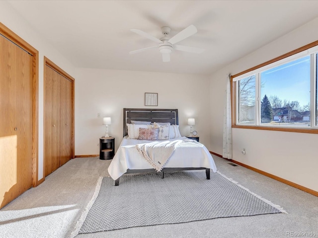 carpeted bedroom featuring ceiling fan and two closets