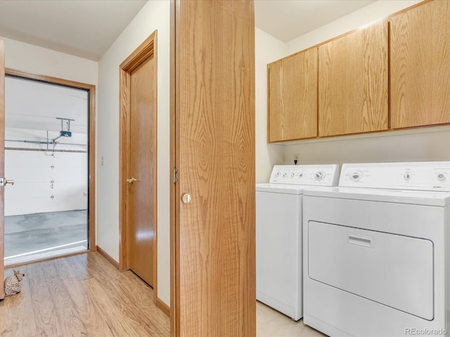 laundry area with light hardwood / wood-style floors, washing machine and clothes dryer, and cabinets