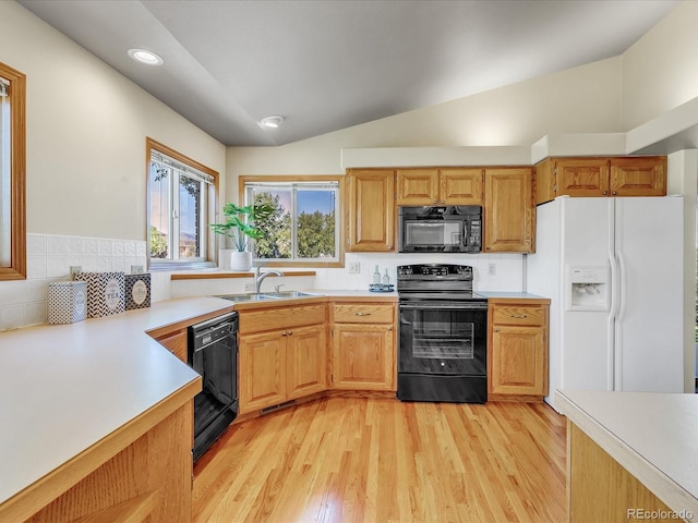 kitchen featuring black appliances, sink, backsplash, vaulted ceiling, and light hardwood / wood-style flooring