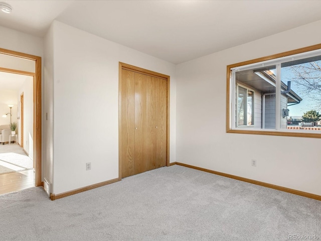 unfurnished bedroom with a closet and light colored carpet