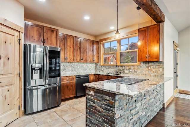 52 Buckskin Ln, Silverthorne, CO 80498 - kitchen featuring black appliances, brown cabinetry, a peninsula, light stone counters, and tasteful backsplash