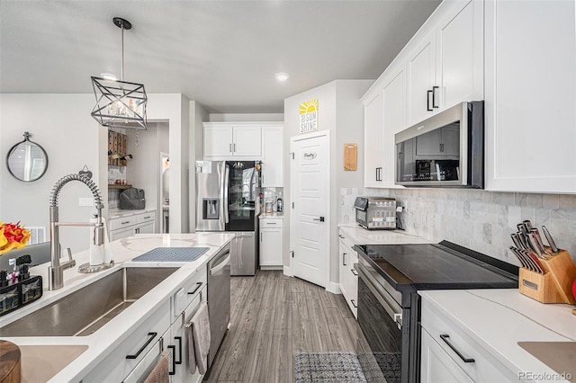 kitchen with sink, white cabinetry, decorative light fixtures, stainless steel appliances, and decorative backsplash