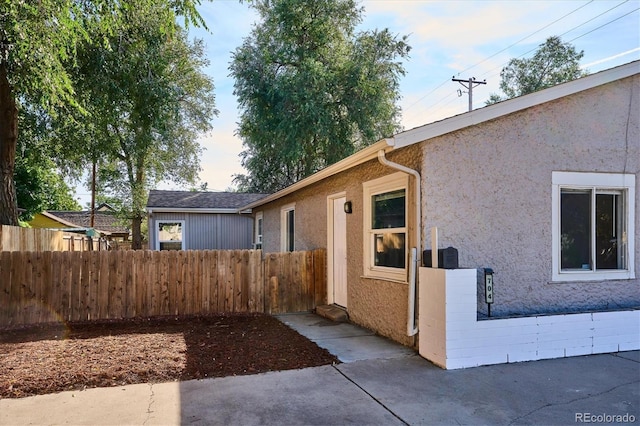 view of front facade with fence, stucco siding, and a patio area