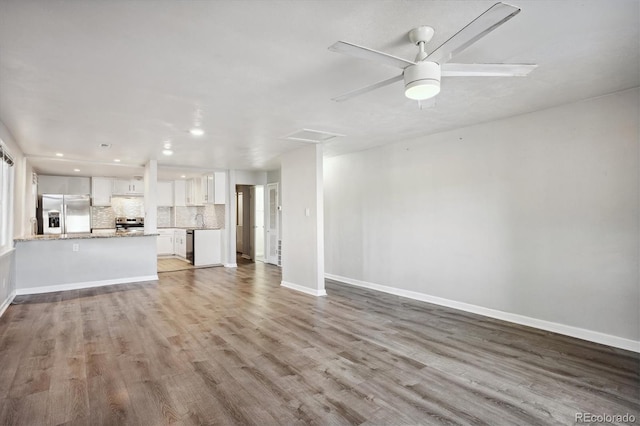 unfurnished living room featuring wood finished floors, baseboards, and recessed lighting