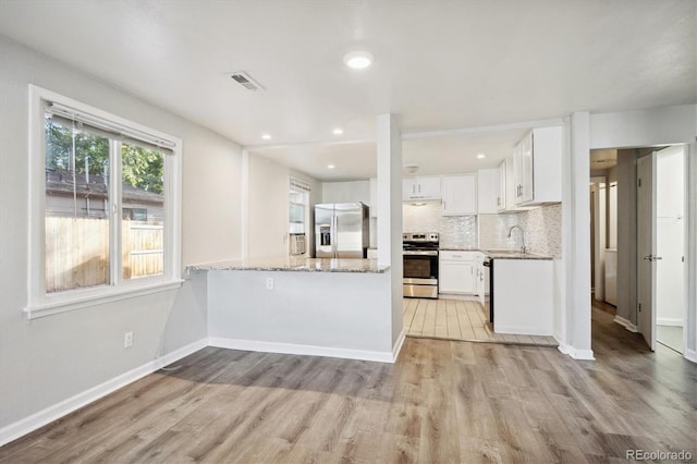 kitchen featuring light wood-style floors, stainless steel appliances, light stone counters, and visible vents