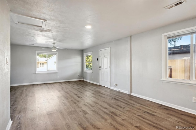 unfurnished room with attic access, baseboards, ceiling fan, visible vents, and wood finished floors