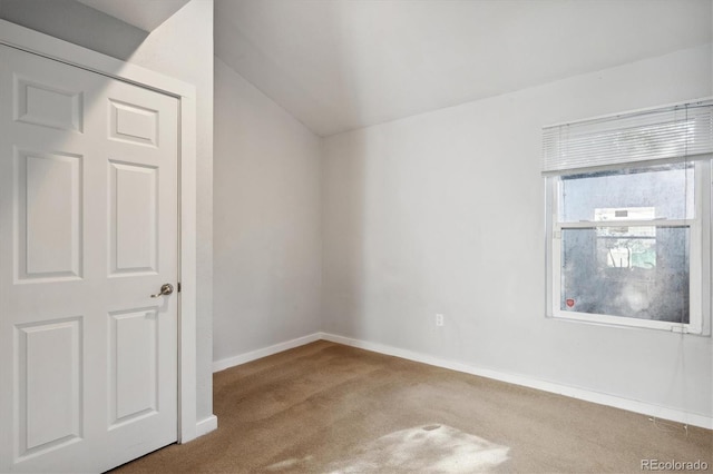 unfurnished room featuring baseboards, carpet floors, and vaulted ceiling