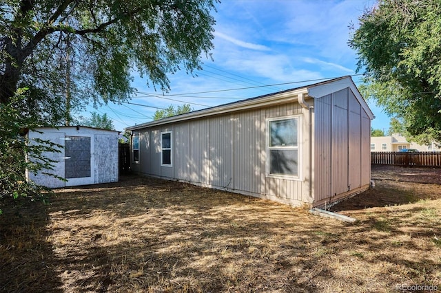 exterior space with an outbuilding, fence, and a storage unit