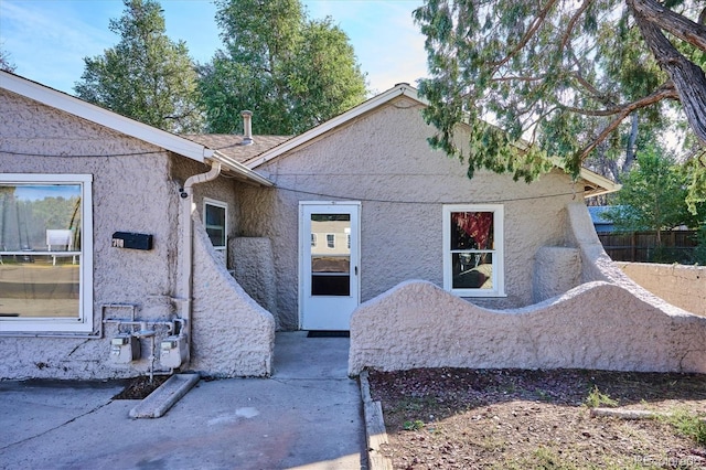 back of property with stucco siding and fence