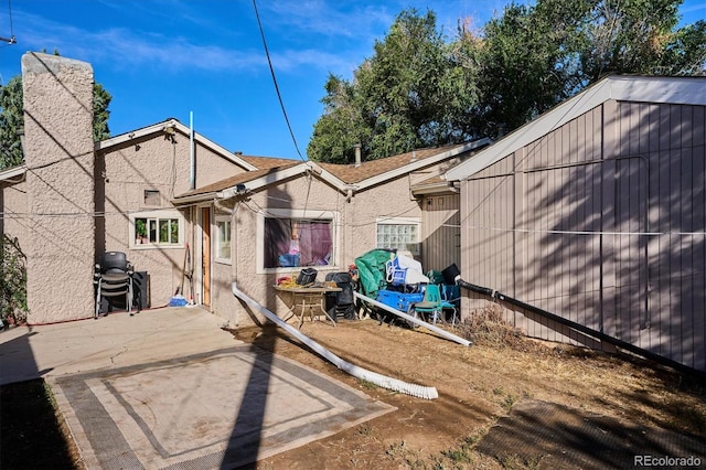 back of property featuring a patio, stucco siding, and a chimney