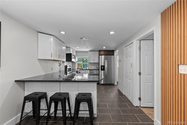 3443 Lawrence St, Denver, CO 80205 - kitchen featuring appliances with stainless steel finishes, a peninsula, white cabinets, a kitchen bar, and recessed lighting