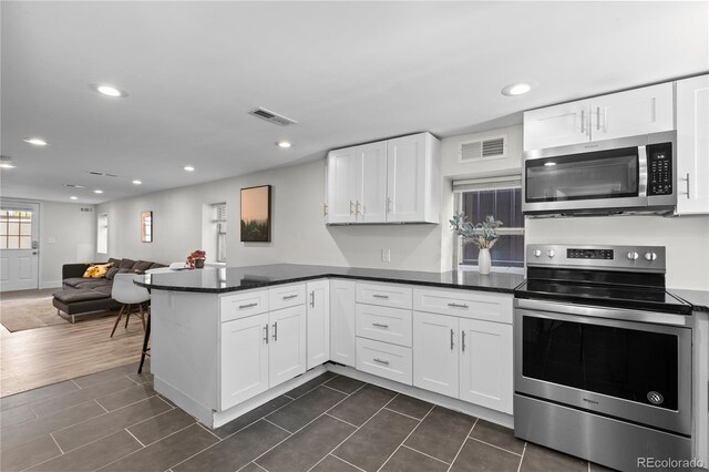 3443 Lawrence St, Denver, CO 80205 - kitchen featuring appliances with stainless steel finishes, white cabinets, a peninsula, recessed lighting, and dark countertops
