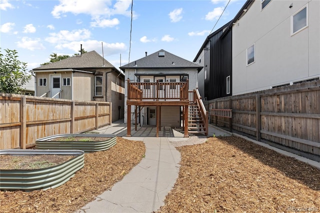 3443 Lawrence St, Denver, CO 80205 - rear view of house featuring a wooden deck, stairway, a fenced backyard, and a vegetable garden