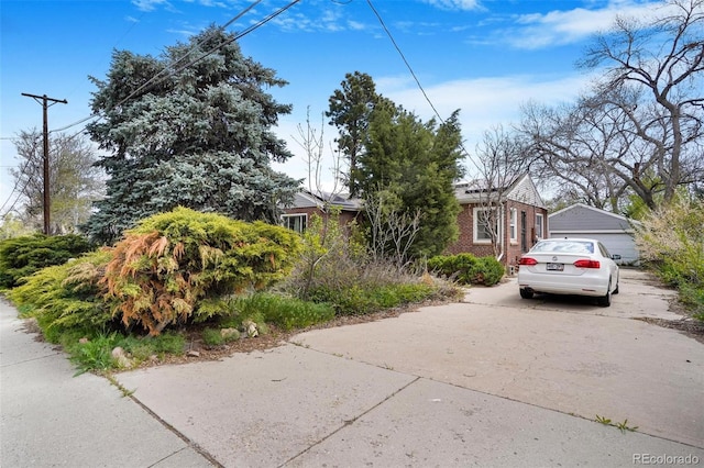 obstructed view of property featuring concrete driveway, brick siding, and a garage