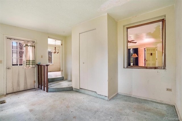 interior space featuring baseboards, ceiling fan with notable chandelier, a textured ceiling, and visible vents