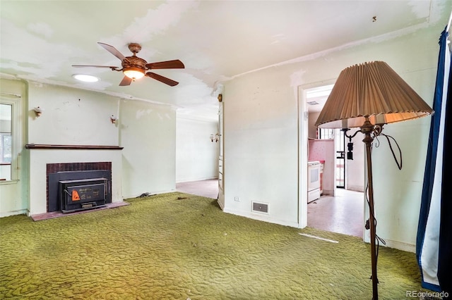 unfurnished living room with visible vents, carpet, ceiling fan, and a fireplace