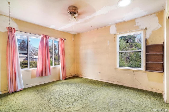 carpeted spare room featuring baseboards and ceiling fan