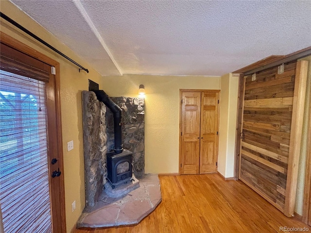 33508 Persistence Ave, Pine, CO 80470 - living room with a textured ceiling, light wood-type flooring, a wood stove, and wooden walls