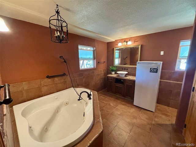 33508 Persistence Ave, Pine, CO 80470 - full bath featuring tile walls, a jetted tub, a textured ceiling, vanity, and tile patterned flooring