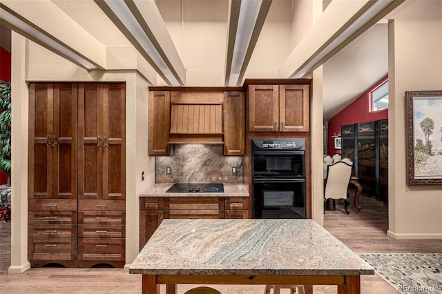 kitchen featuring light stone counters, light wood-type flooring, decorative backsplash, and black appliances