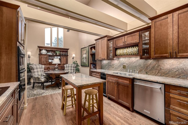 kitchen featuring sink, a breakfast bar, dishwasher, light stone countertops, and light wood-type flooring