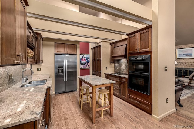 kitchen with light hardwood / wood-style floors, light stone countertops, sink, and black appliances