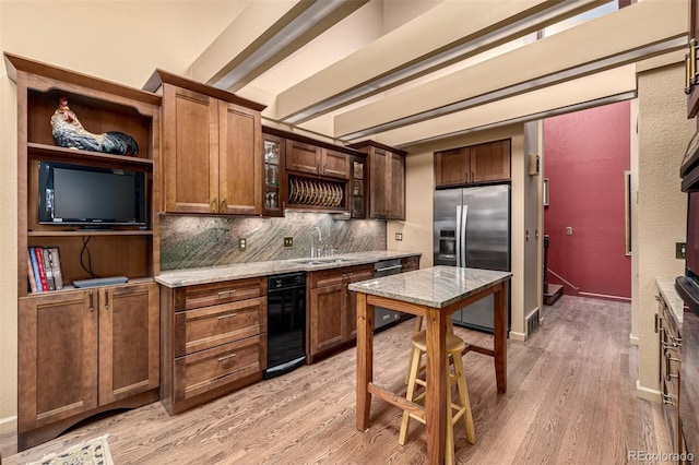 kitchen featuring sink, tasteful backsplash, appliances with stainless steel finishes, light stone countertops, and light hardwood / wood-style floors