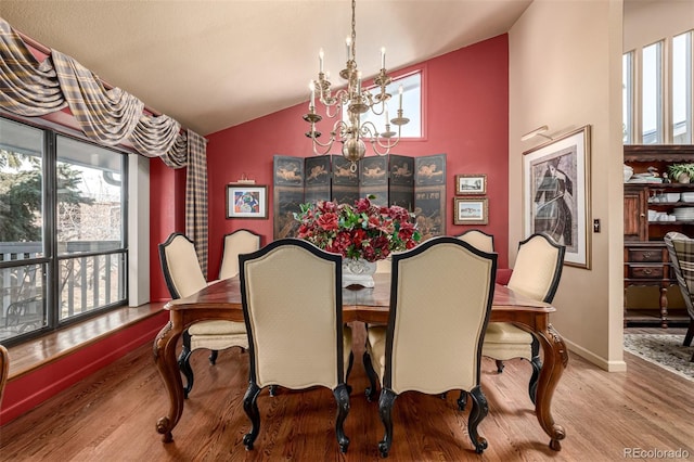 dining room with lofted ceiling, light hardwood / wood-style floors, and a notable chandelier