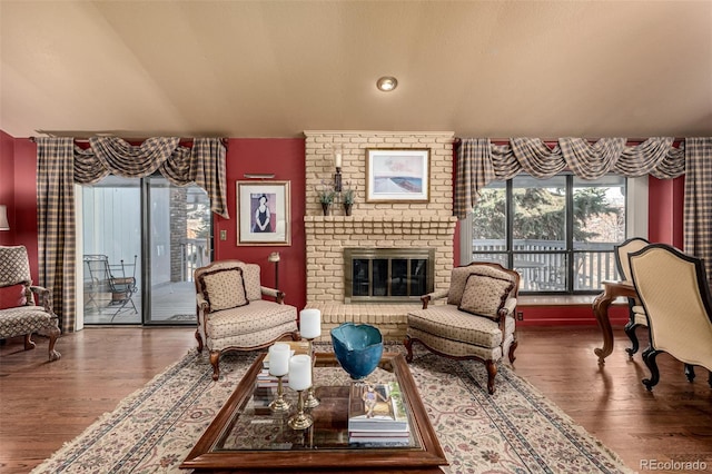 living room with a brick fireplace and wood-type flooring