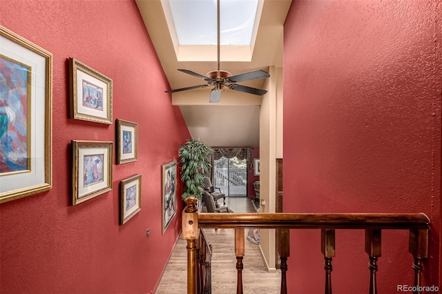 stairway with ceiling fan, a skylight, and hardwood / wood-style floors