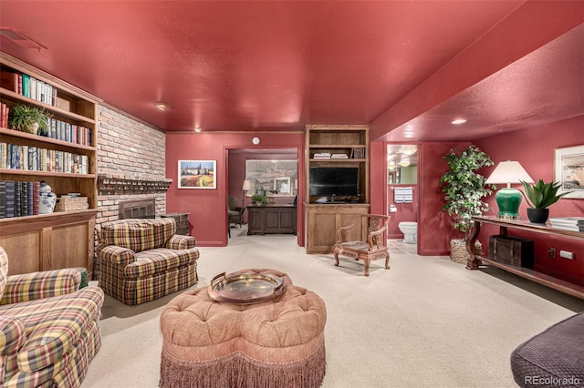 living room with a brick fireplace, light colored carpet, and a textured ceiling